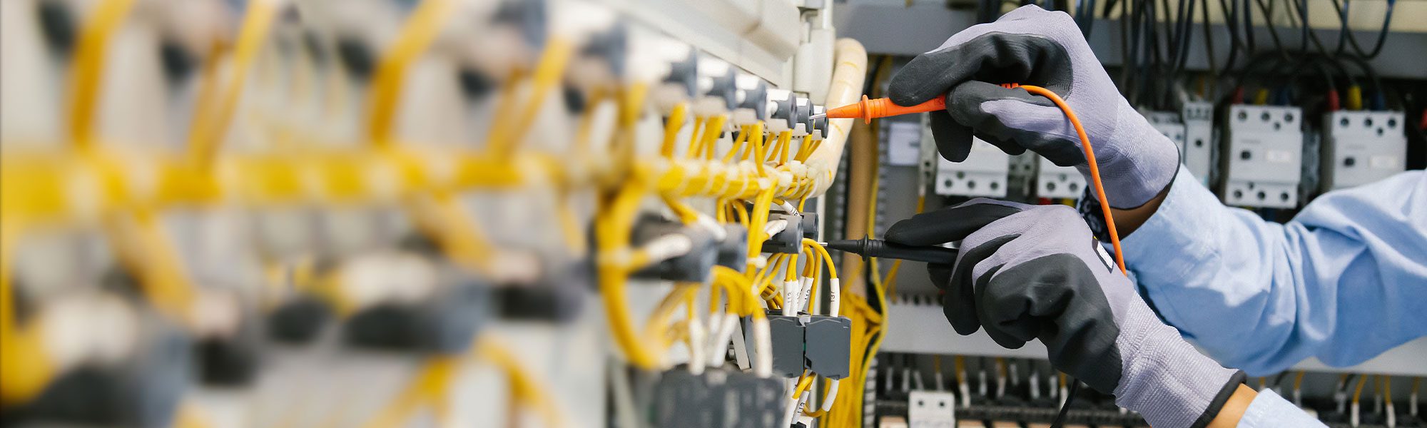 Elektriker arbeitet mit Handschuhen an einem Verteiler
